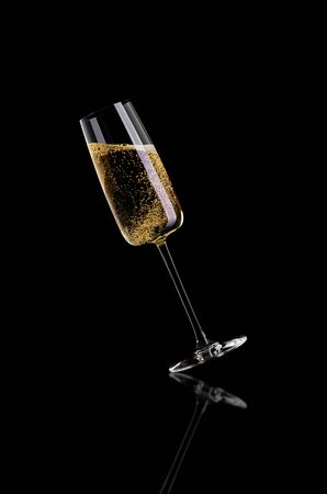 A glass of champagne, without the foam on a dark background is tilted to the left.の写真素材