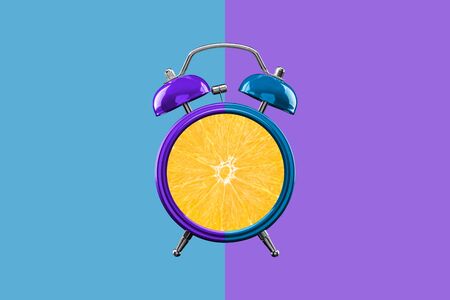 Alarm clock in purple and turquoise on a contrasting background. A sliced orange instead of a clock...