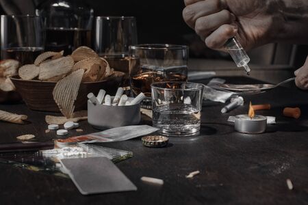 Various drugs, alcohol and cigarettes are on the wooden table. Substances that cause drug and alcohol dependence. Low key.の写真素材