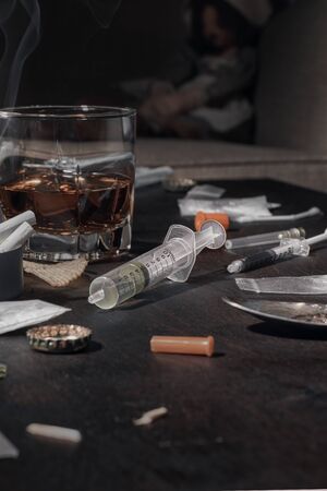 Various drugs, alcohol and cigarettes are on the wooden table. Substances that cause drug and...