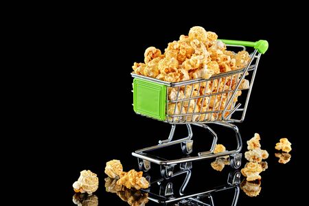 Cart on wheels with popcorn isolated on a dark background.の写真素材