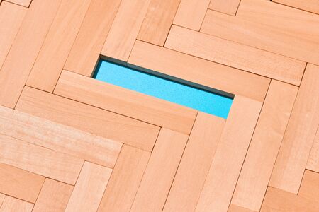 Wooden planks laid with a herringbone pattern on a light blue background in the center is an empty...