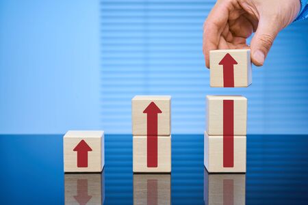 Business concept of the process of growth, increase in revenue, price. Wooden cubes on a blue...