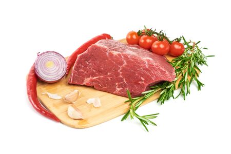A large piece of fresh meat tenderloin, with rosemary, red pepper, garlic and cherry tomatoes lies on the cutting board on a white background. A fresh piece of knuckle.の写真素材