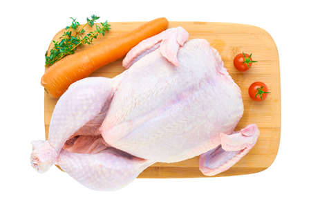 Fresh raw chicken carcass on a wooden cutting Board with vegetables, isolated on a white background. The view from the top.の写真素材