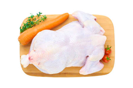 Fresh raw chicken carcass on a wooden cutting Board with vegetables, isolated on a white background. The view from the top.の写真素材