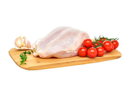 Fresh raw chicken breast on a wooden cutting Board with vegetables and herbs, on a white background. Close up.の写真素材