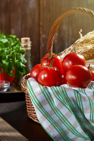 Ripe red tomatoes in a basket on a wooden table. Still life with the autumn harvest of vegetables.の写真素材