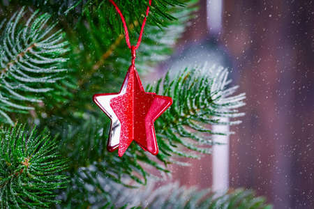 Christmas background with a spruce branch, a red star on a branch and falling snow. New year's background with free space for text.の写真素材