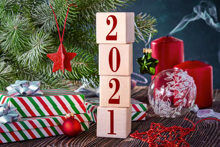 Cubes with numbers 2021 on a Christmas background with gifts in boxes, decorated with a spruce branch and extinguished candles. New year's background with free space for text.の写真素材