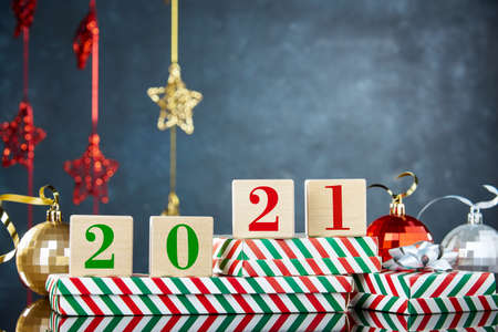 Cubes with the numbers 2021 on the box with a Christmas gift on the background of Christmas decorations. New year's background, free space for text.の写真素材