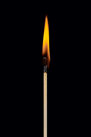 A single burning match with the flame rising up, isolated on a black background. Free space for text, layout for design.の写真素材