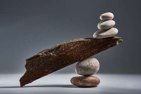 Balancing pyramid of sea pebbles on a gray background, the concept of harmony and balance, heavy and...