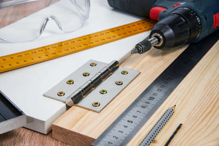 Installation of furniture hinges in the chipboard, tools and accessories needed to perform the work. Small carpentry work at home, the concept of a home master, self-repair of the houseの写真素材