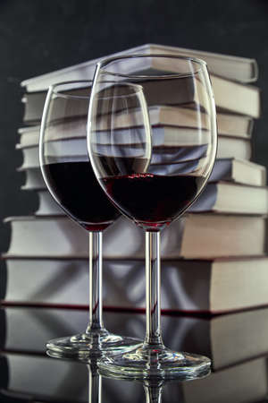 Two glasses of red wine against a stack of books, close-up. Free space for text.の写真素材