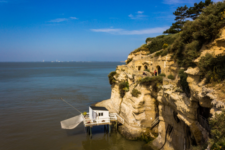 A white fishing hut next to some old walkways that cut through the cliffsのeditorial素材