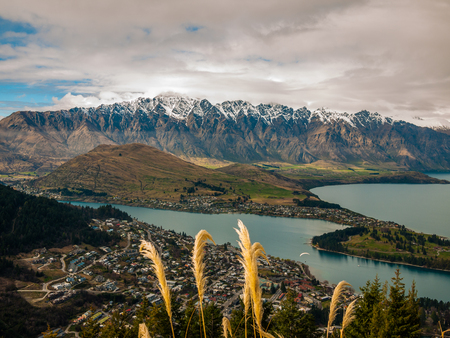 Cloudy sky snowy mountains and a town by a lakeの写真素材