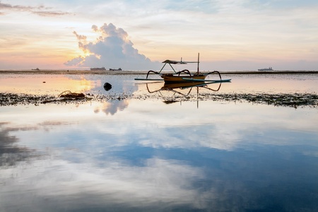 Holiday in Bali, Indonesia - Reflection Sunrise in Tanjong Benoa with boatの写真素材