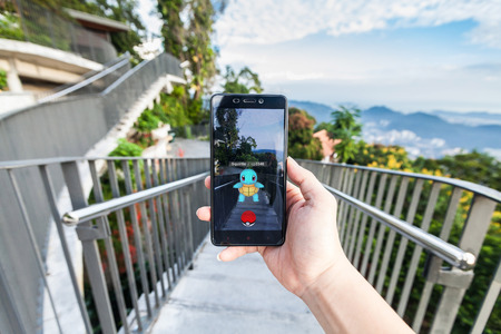 California, United States - July 23, 2016: Close up of a man holding a smartphone while playing Pokemon Go game and try to catch a Pokemonのeditorial素材