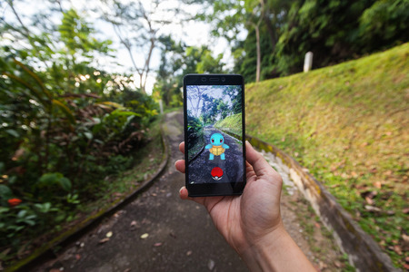 California, United States - July 23, 2016: Close up of a man holding a smartphone while playing Pokemon Go game and try to catch a Pokemonのeditorial素材