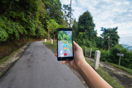 California, United States - July 23, 2016: Close up of a man holding a smartphone while playing Pokemon Go game and try to catch a Pokemonのeditorial素材