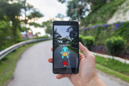 California, United States - July 23, 2016: Close up of a man holding a smartphone while playing Pokemon Go game and try to catch a Pokemonのeditorial素材