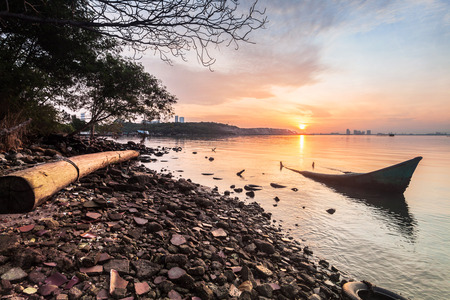 Sunrise by the shore with silhouette of broken boatの写真素材