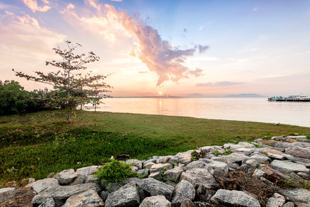 Sunrise by the shore with silhouette of broken boatの写真素材