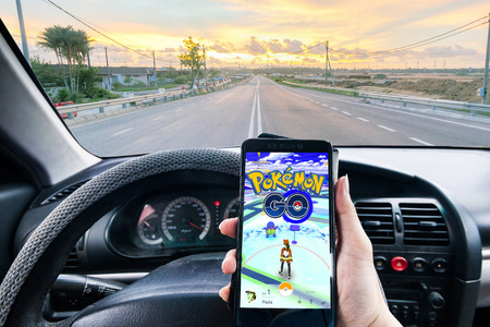 California, United States - July 16, 2016: Hand holding a cellphone loading Pokemon Go game while drivingのeditorial素材
