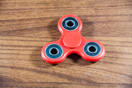 Fidget Spinner in wooden isolated background for stress release during workの写真素材