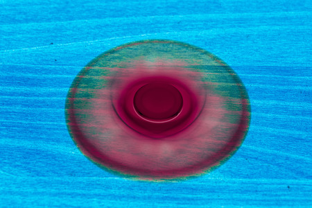 Fidget Spinner in fluorescent UV glowing isolated background for stress release during workの写真素材