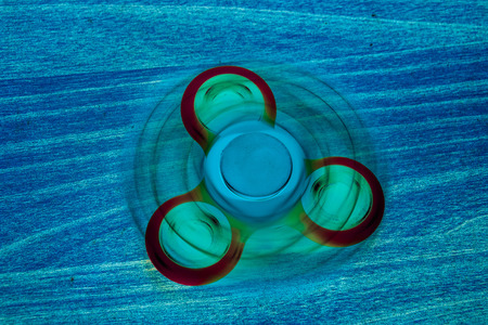 Fidget Spinner in fluorescent UV glowing isolated background for stress release during workの写真素材