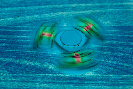 Fidget Spinner in fluorescent UV glowing isolated background for stress release during workの写真素材