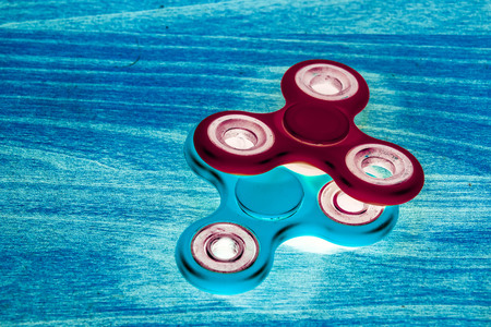 Fidget Spinner in fluorescent UV glowing isolated background for stress release during workの写真素材