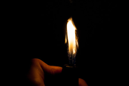 Close up view of real sparking light from lighter in dark black backgroundの写真素材