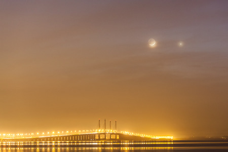 Penang Bridge view from the shore of George Town, Malaysia with venus and moon as backgroundの写真素材