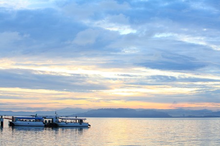 Boat resting near a jetty with sunrise backgroundの写真素材