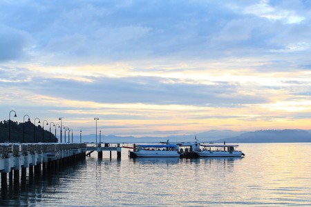 Boat resting near a jetty with sunrise backgroundの写真素材