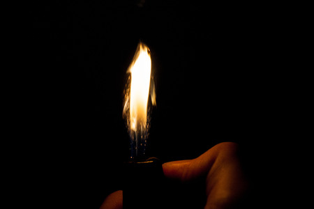 Close up view of real sparking light from lighter in dark black backgroundの写真素材