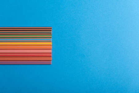 Left rainbow of pencils over blue copy space on the right
