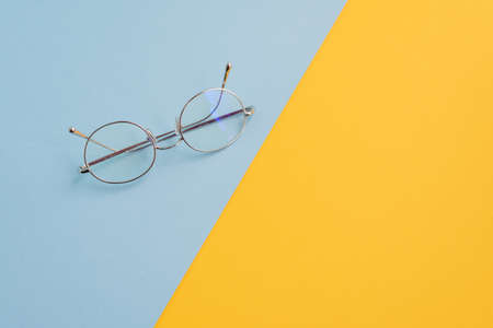 Eyeglasses desk concept blue and yellow with copy spaceの写真素材