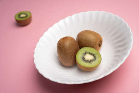 Kiwis on white bowl over pink table and half blurredの写真素材