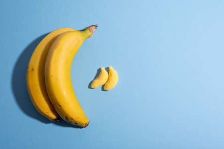 Fruit vs candy. Yellow bananas over blue with copy space, design, comparing. Healthy eating concept. Spanish, European Union agricultural product. Geographical Indication. Children dessertの写真素材