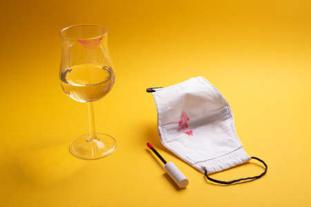 White wineglass marked and white crafted facemask with red kiss mark inside. Outside partying, going out in new normality concept. Love in pandemic conceptの写真素材