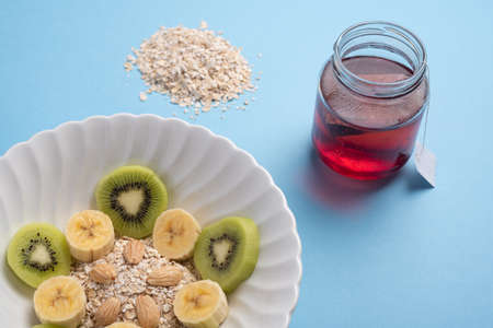 Fruits, almond and cereal meal. Healthy food concept on blue plain background. Raw ingredient next to dishの写真素材