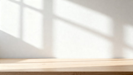 Wooden table top on white wall background with shadow from window.の素材