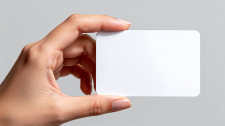 Close-up of female hand holding blank business card on gray backgroundの素材
