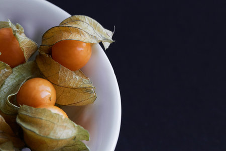 Cape gooseberry (Physalis peruviana) in white bowl on black backgroundの写真素材