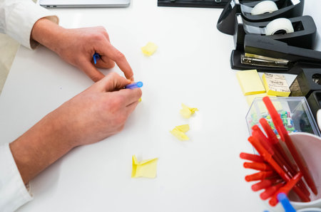 Close-up of female hands writing on sticky notes in the officeの写真素材