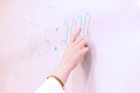 Female teacher writing on the whiteboard in classroom. Education concept.の写真素材